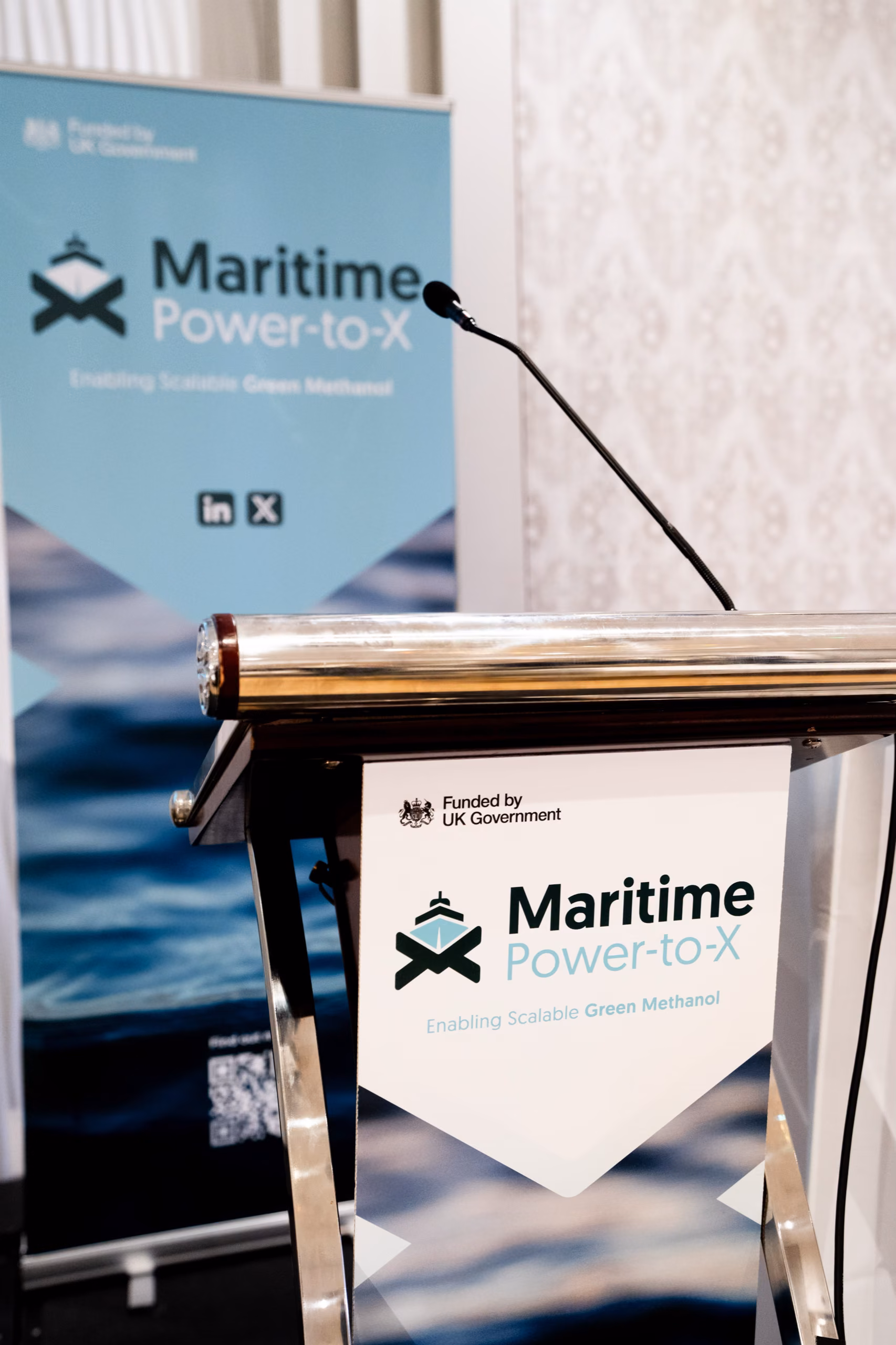 A lectern and banner with the Maritime Power-to-X logo at a project event